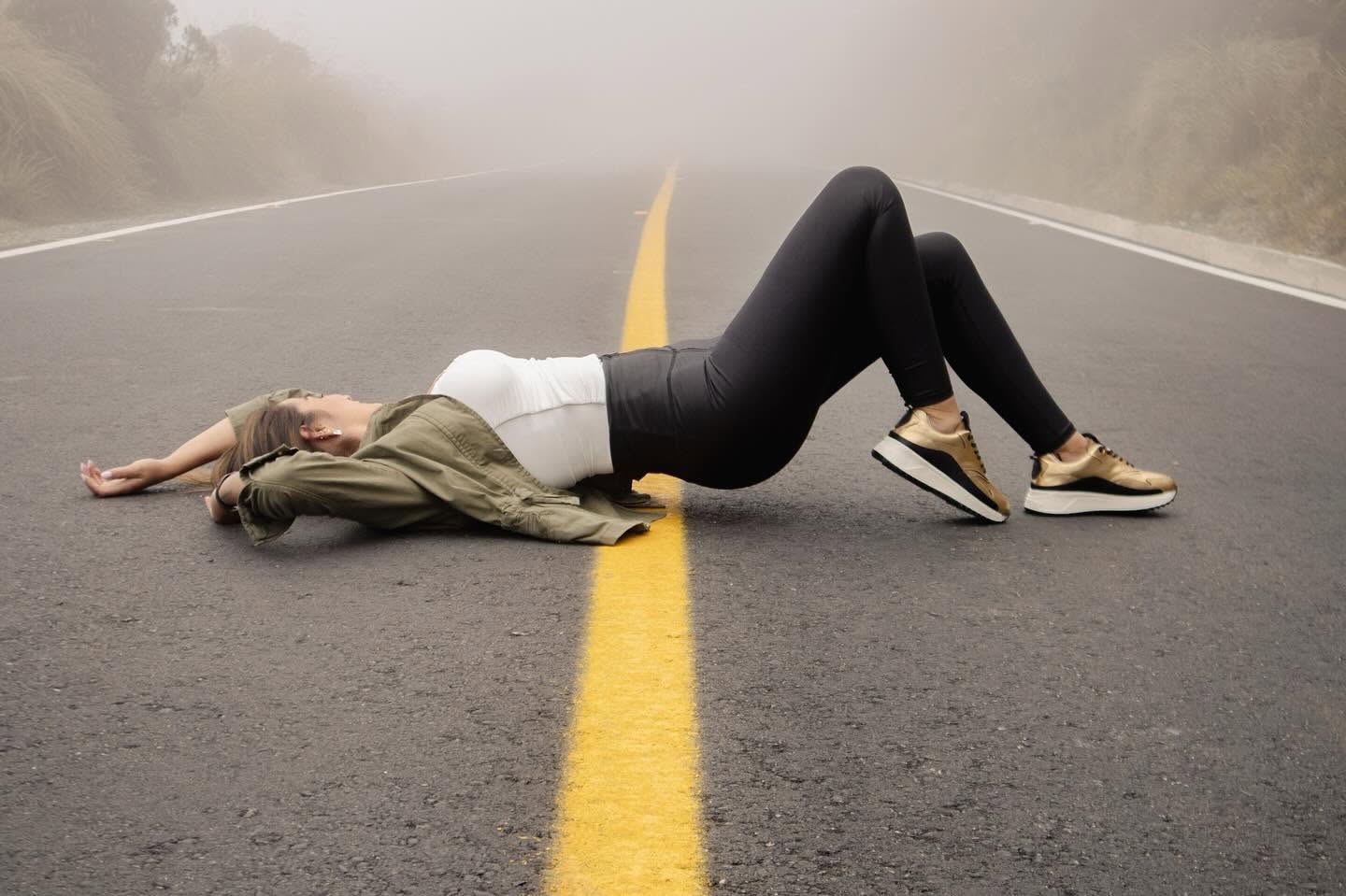 Sesión de moda Geratto con tenis dorados en una carretera entre la niebla
